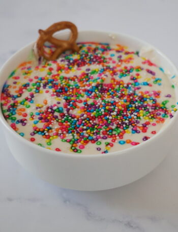 White cakebatter dip in a white bowl with rainbow sprinkles