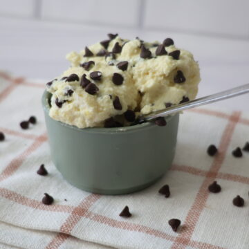 Vanilla pudding with chocolate chips in a blue-green bowl with a silver spoon.
