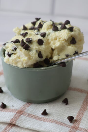Vanilla pudding with chocolate chips in a blue-green bowl with a silver spoon.