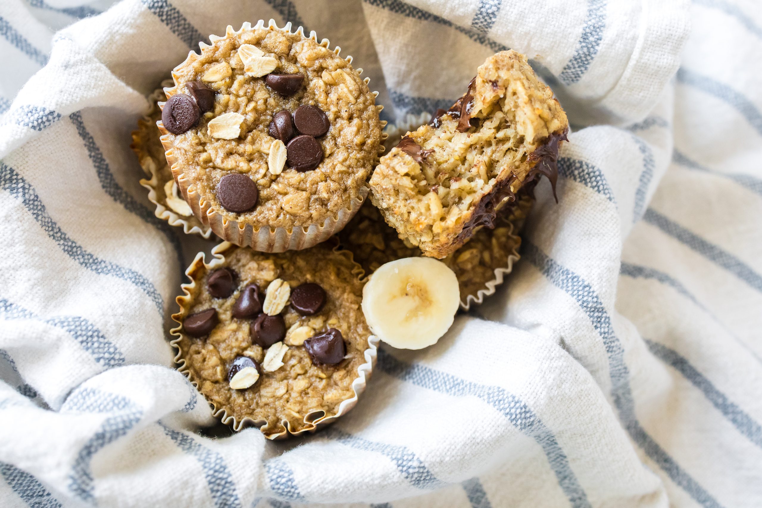 Banana oat muffins in a basket with a blue and white linen napkin. 