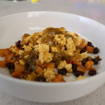 scrambled eggs, potatoes, black beans and peppers in a white bowl
