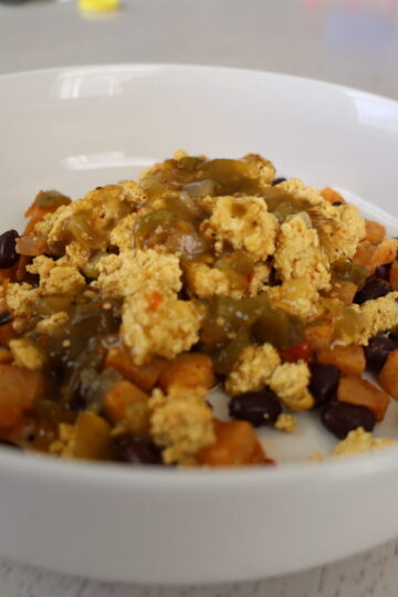 scrambled eggs, potatoes, black beans and peppers in a white bowl