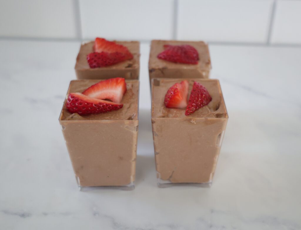 Chocolate, creamy cheesecake filling in 4 clear rectangular cups.