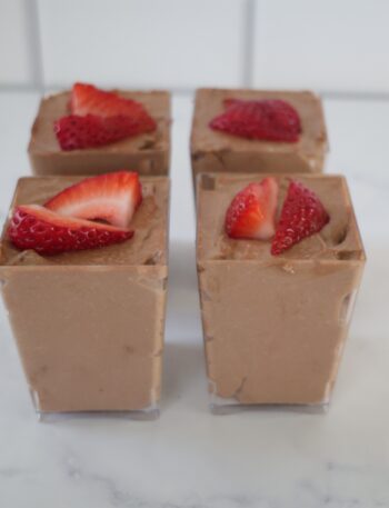 Chocolate, creamy cheesecake filling in 4 clear rectangular cups.