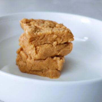 Four squares of peanut butter fudge stacked alternatingly in a white bowl.