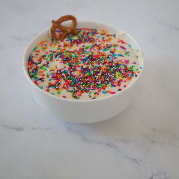 A white cake batter dip with rainbow sprinkles in a small white bowl.
