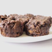 4 dark-chocolate, muffins on a white plate with a white background