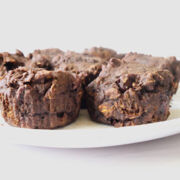 4 dark-chocolate, muffins on a white plate with a white background