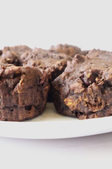 4 dark-chocolate, muffins on a white plate with a white background