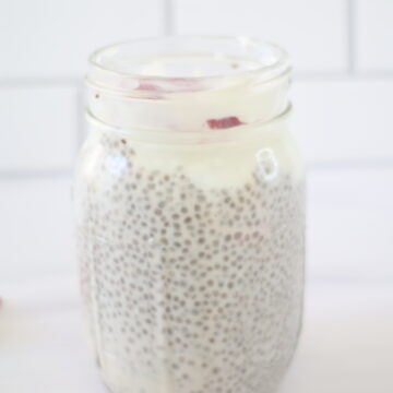 A clear, glass, mason jar with a strawberries and cream chia pudding