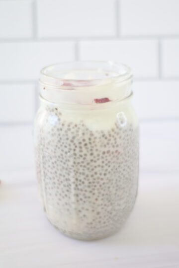 A clear, glass, mason jar with a strawberries and cream chia pudding