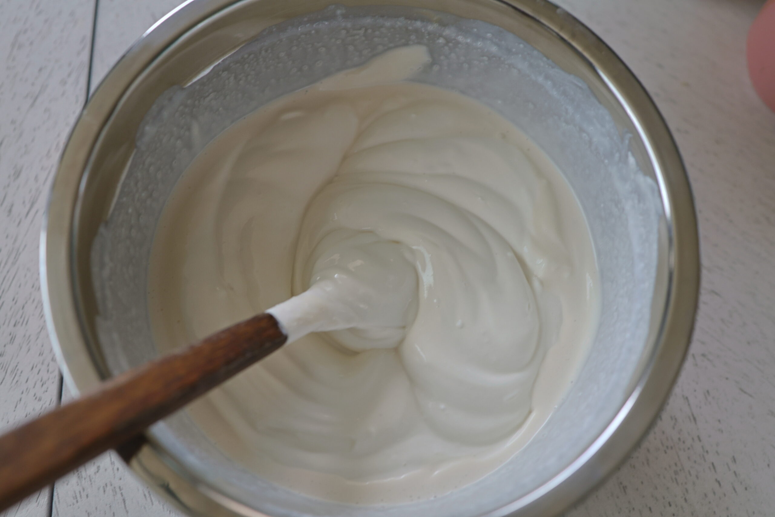A silver bowl with yogurt, whipping cream and sugar. 