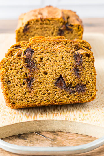 Slice gluten-free almond flour pumpkin bread with chocolate chips served on a wooden cutting board.