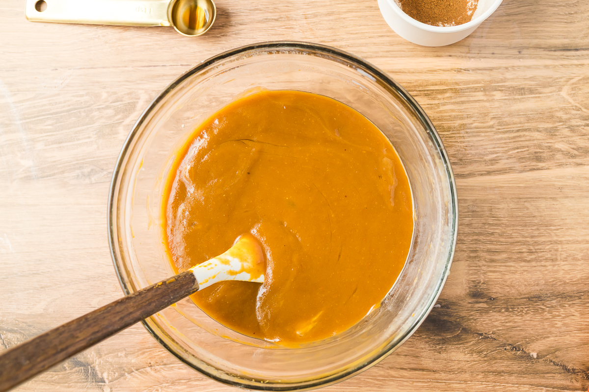 Pumpkin, sugar, vanilla and eggs in a clear mixing bowl.