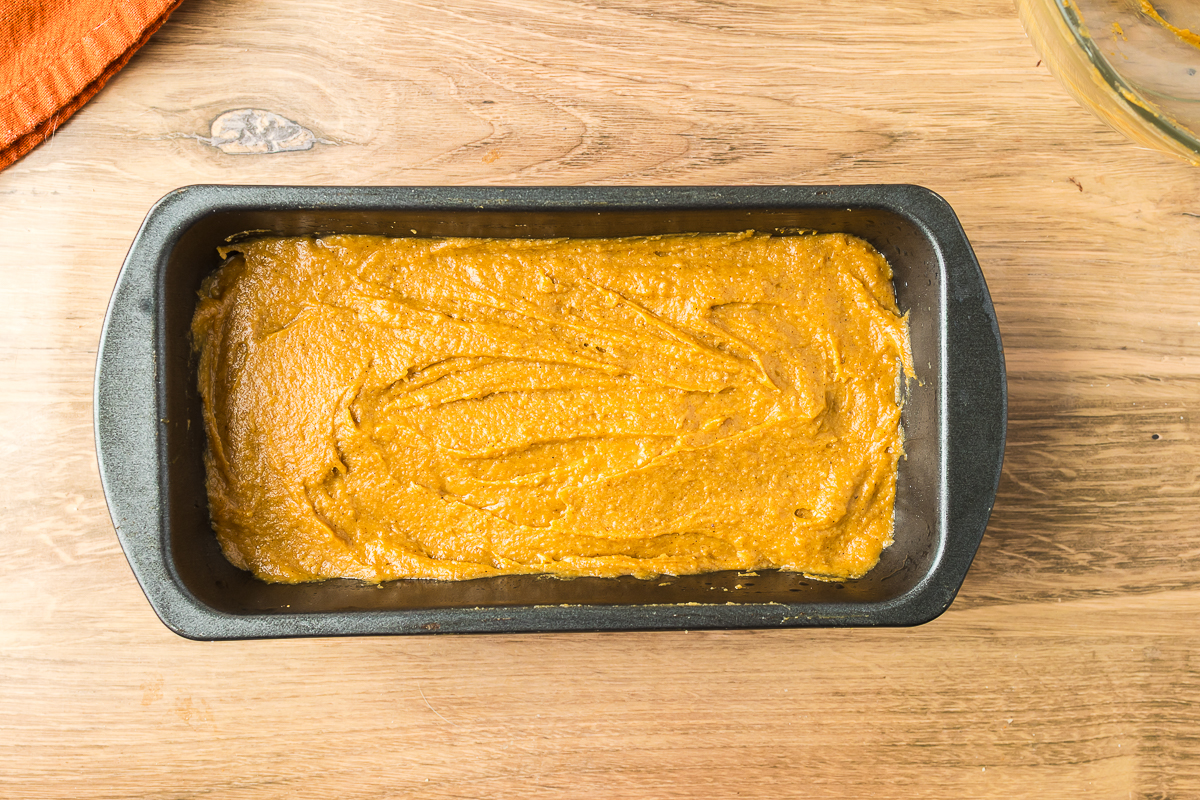 Almond flour pumkin batter spread in a grey loaf pan.