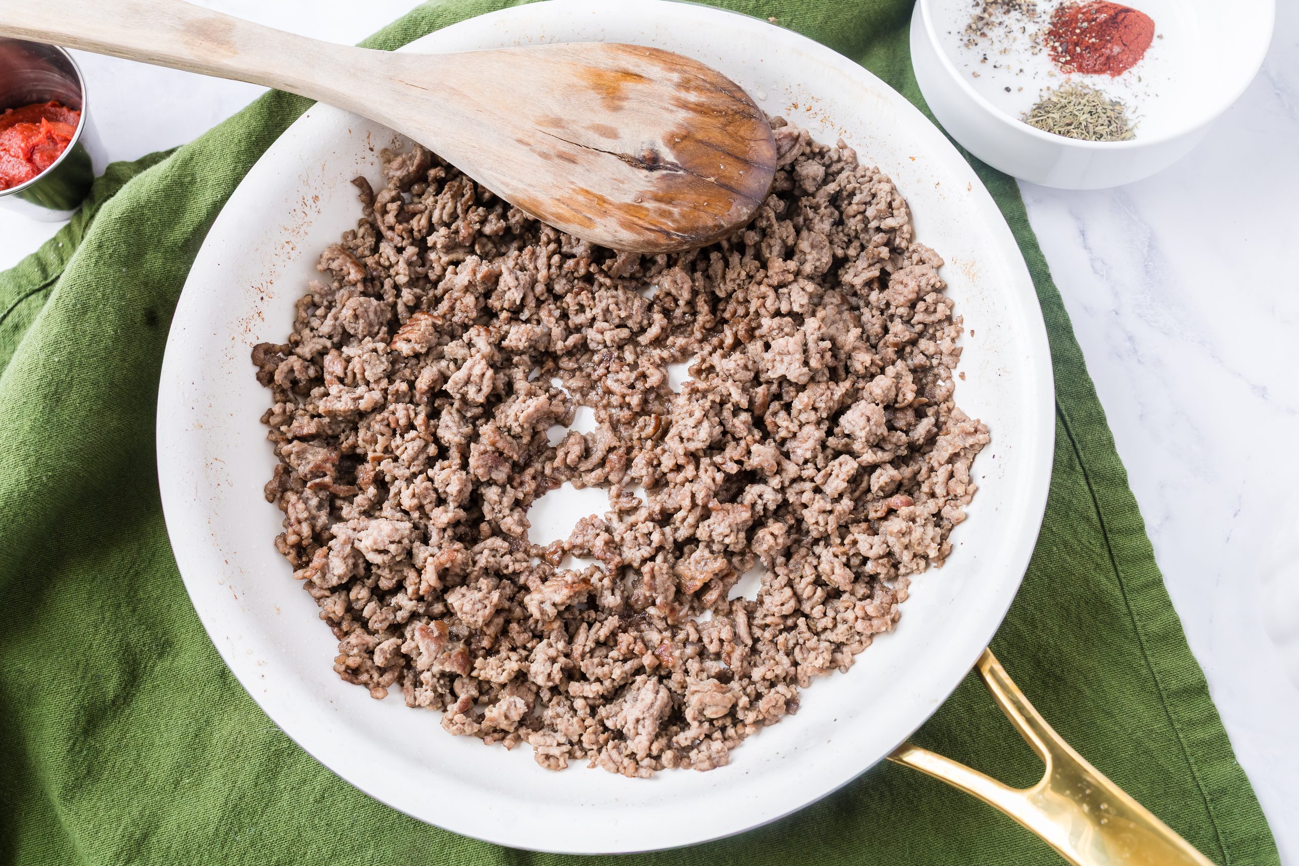 Ground beef in a white and gold skillet.