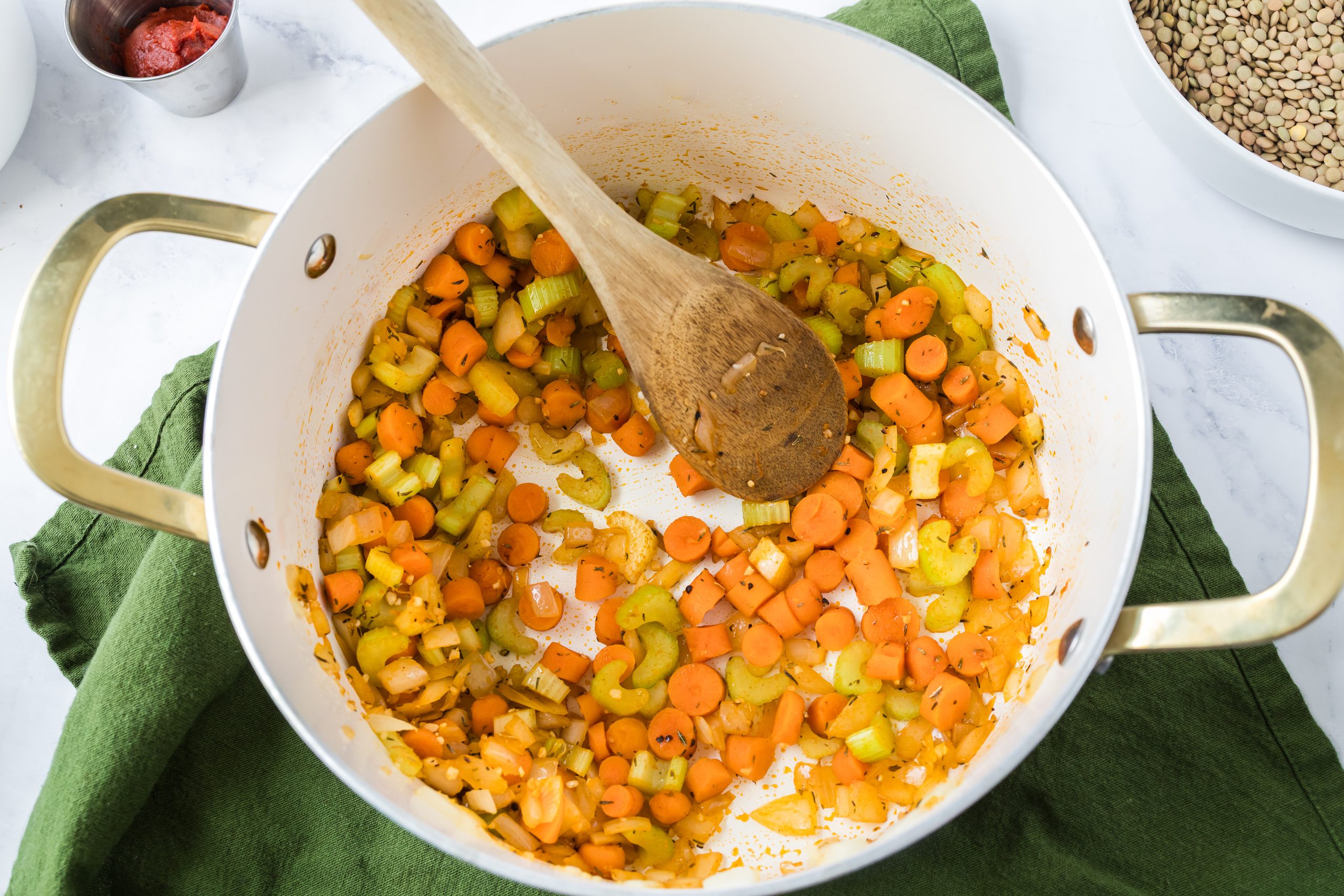Chopped celery and carrots in a white and gold pot.