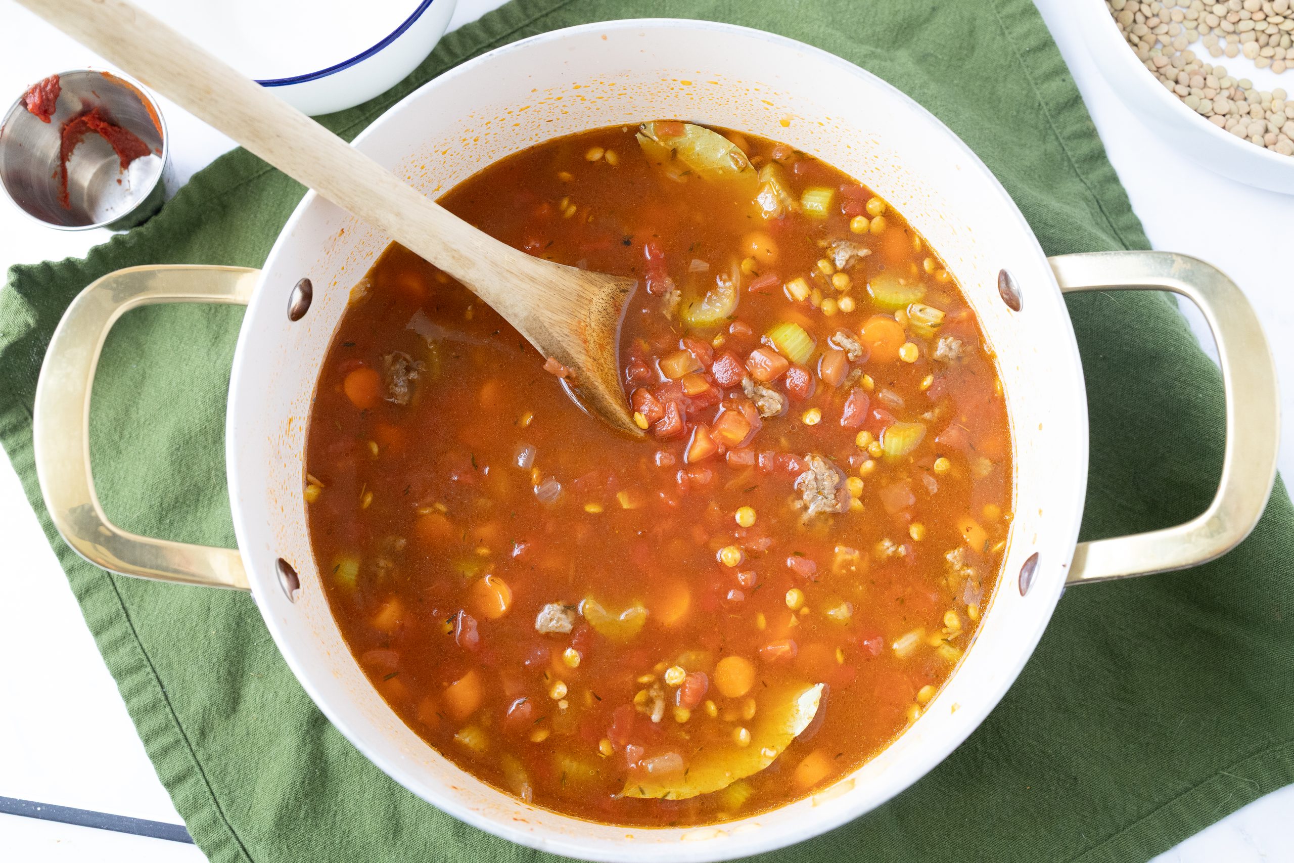 Mixed vegetables with lentils, tomatoes and broth in a white and gold pot. 